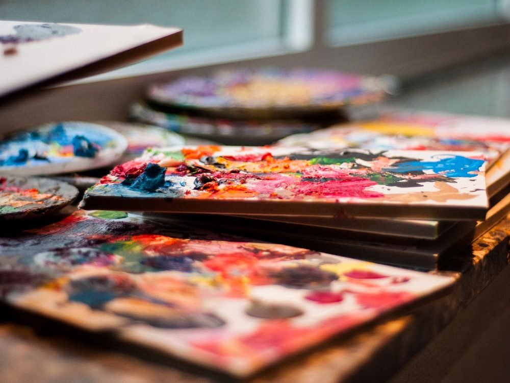 Paletas con pintura de muchos colores sobre una mesa de trabajo